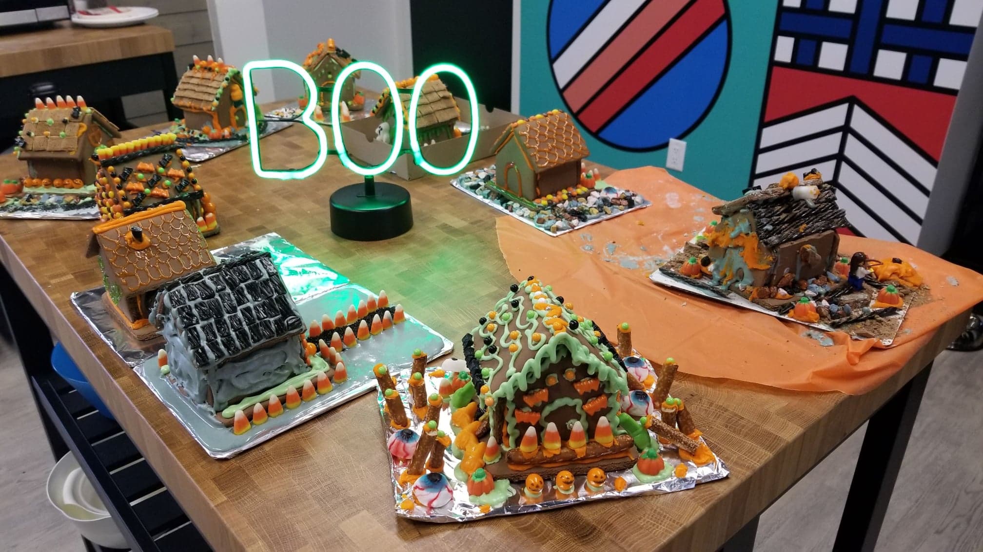 Halloween gingerbread houses made by the Kick Point team, an illuminated BOO sign at the centre of the table