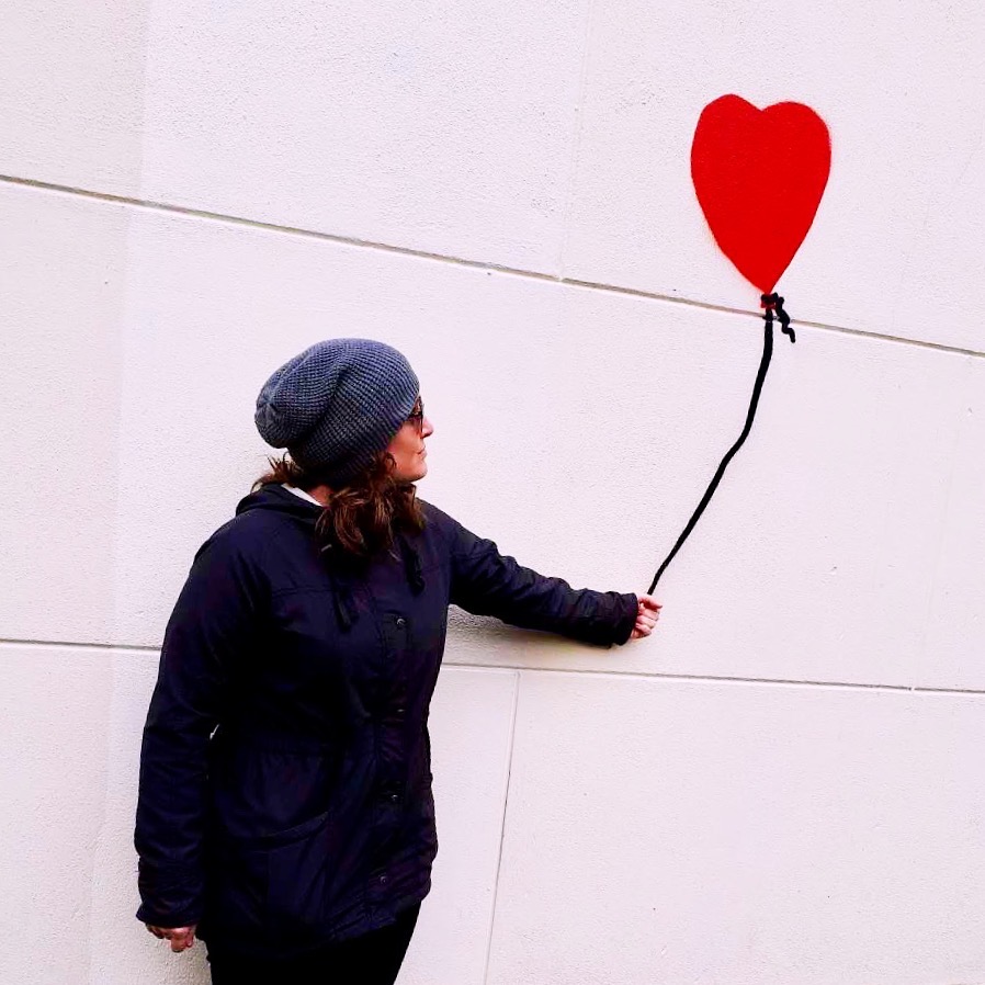 Emma pretends to hold a heart balloon painted on a wall