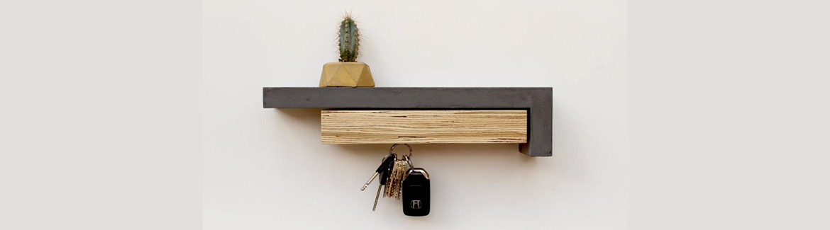 Keys hang from a magnetic key holder made of concrete and wood. A cactus in a yellow pot sits above
