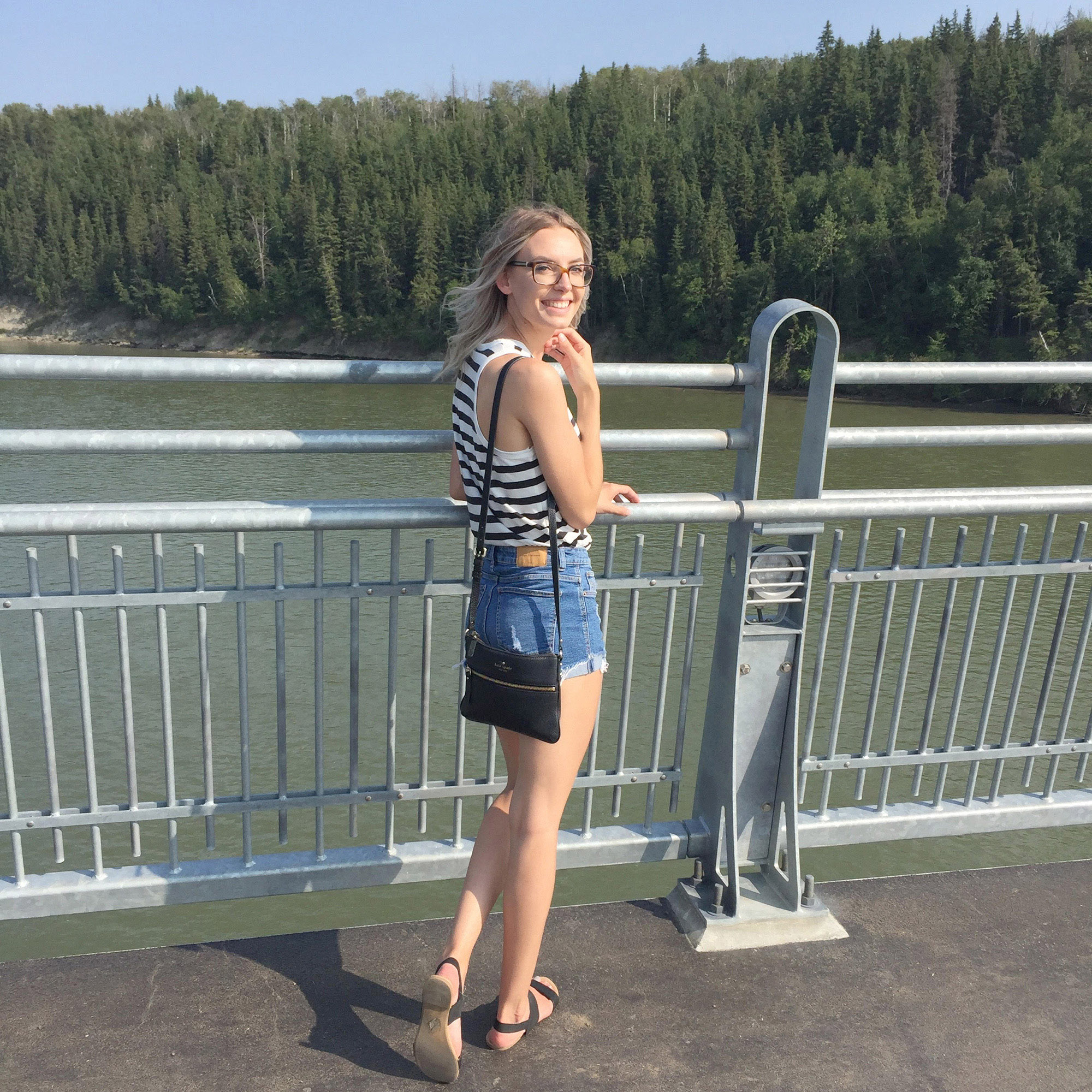Liz smiles at the camera while standing on a bridge over the North Saskatchewan River