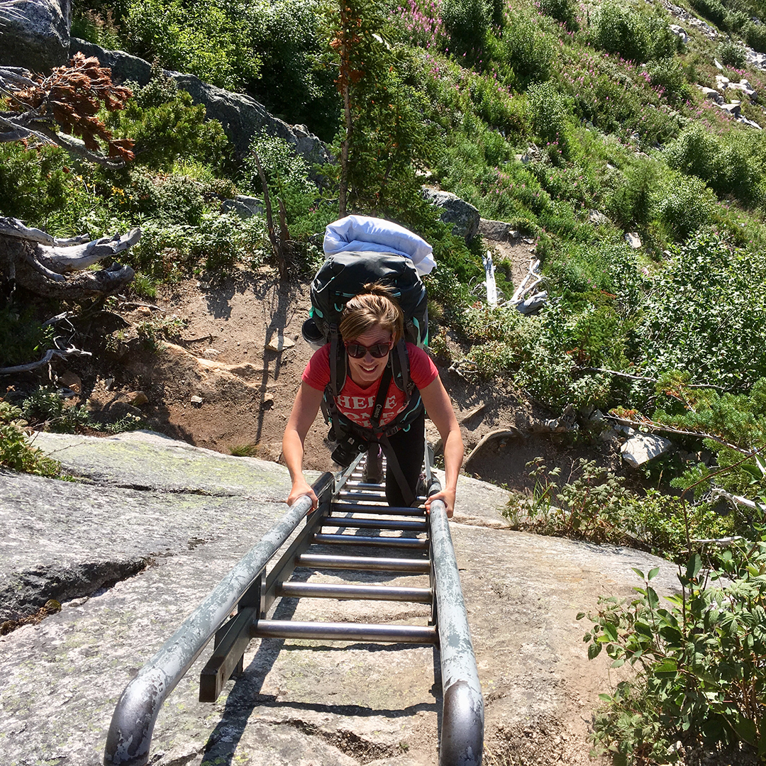Penny climbs a ladder on the side of a mountain