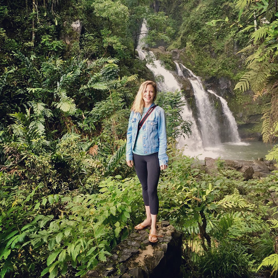 Penny smiles while standing in front of a waterfall