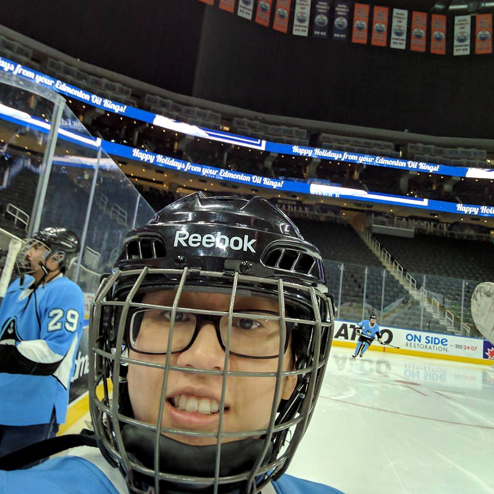 A selfie of a Renee, who is playing hockey in Rogers Place, with Oilers flags in the background