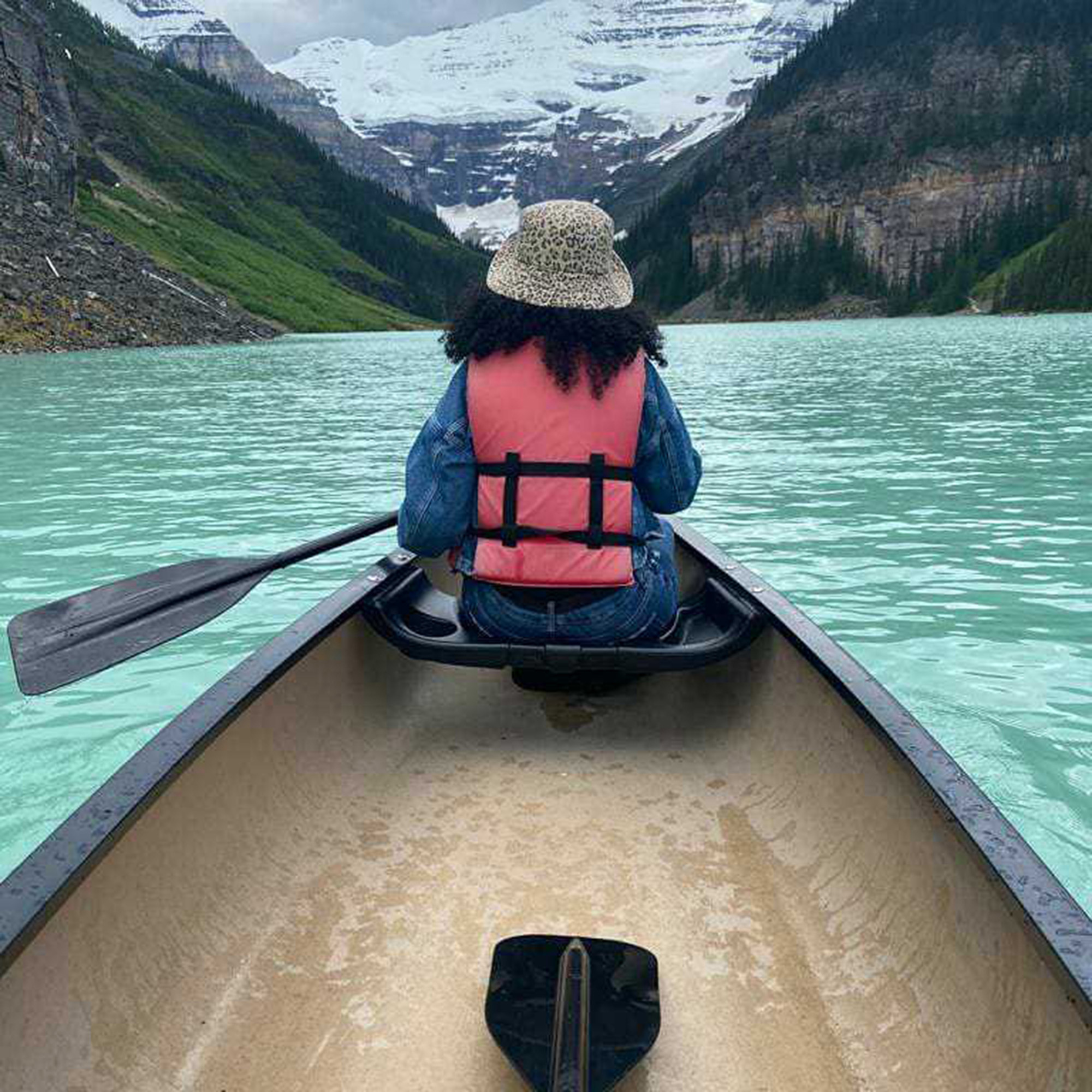 Firdous sits in a canoe, on Lake Louise, with her back to the camera