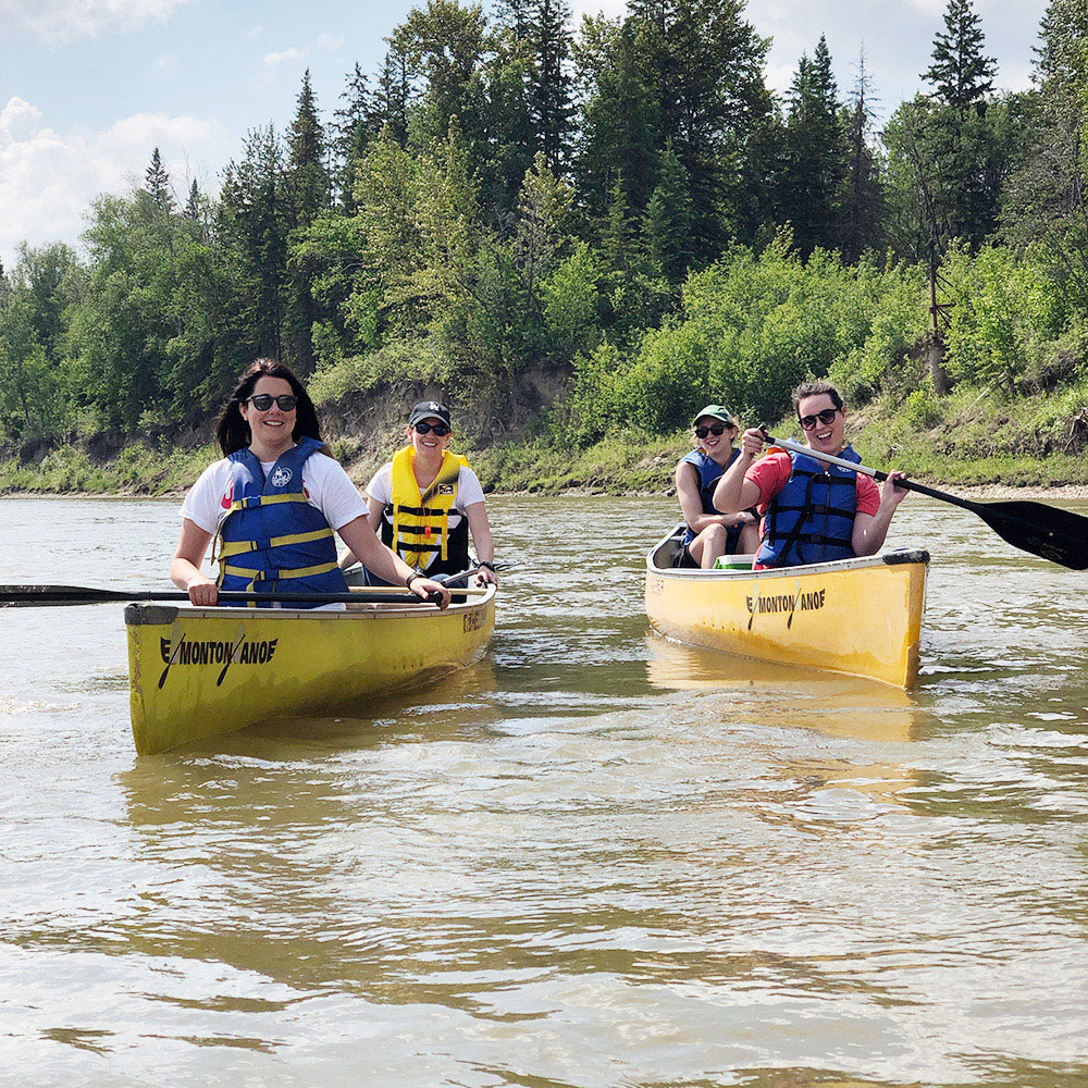 Kick Point team canoes down the North Saskatchewan river, four team members in two yellow canoes