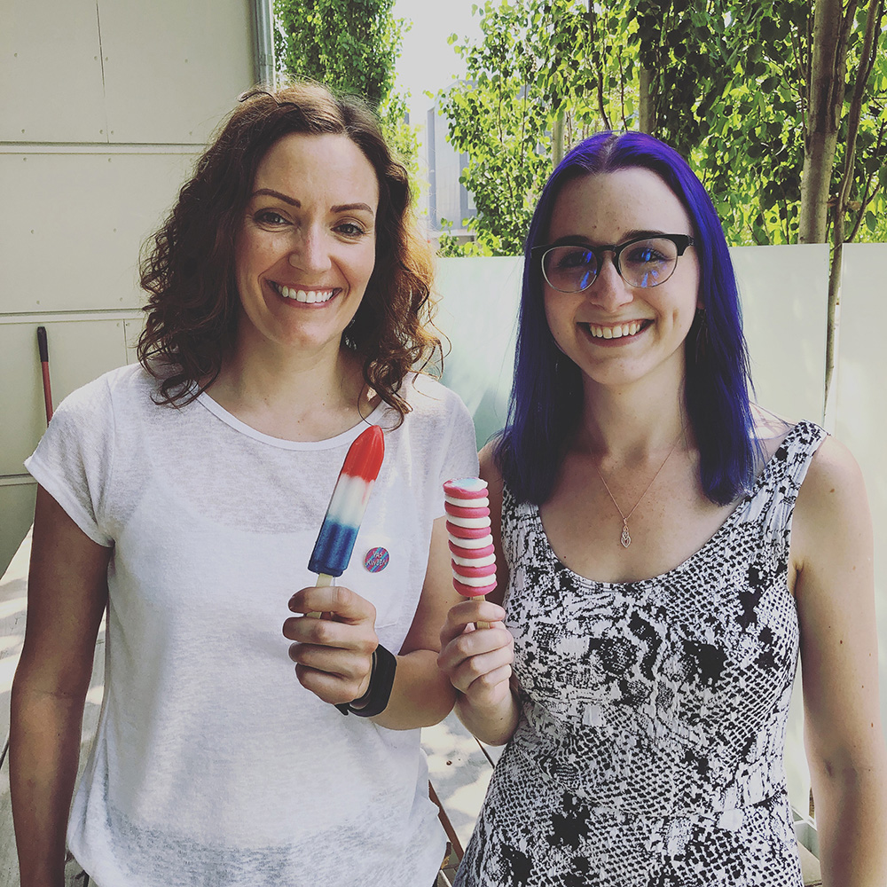Sarah and Brittany smile while holding popsicles.