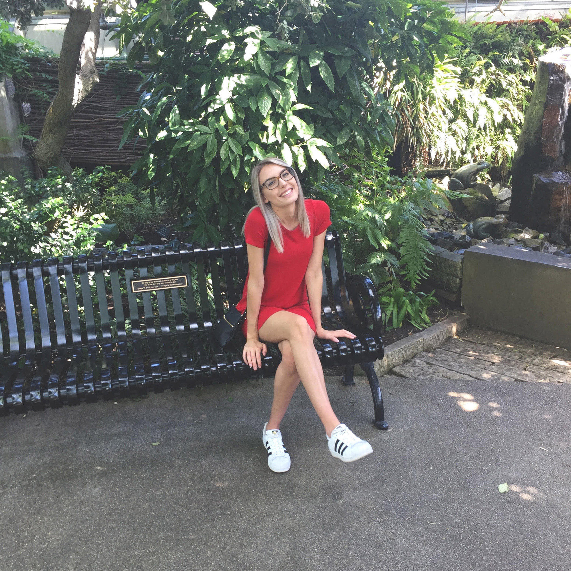 Liz sitting on a bench in a red dress