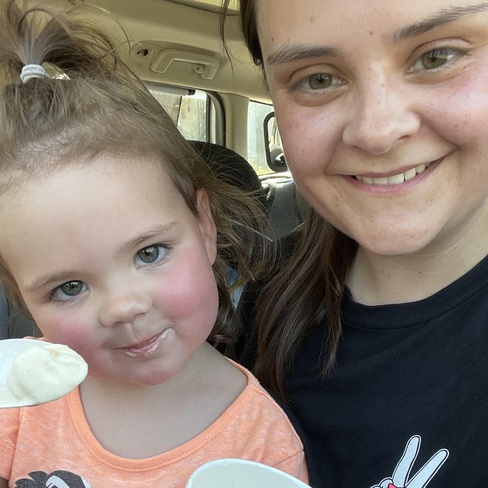 Amy and her daughter smile while eating ice cream
