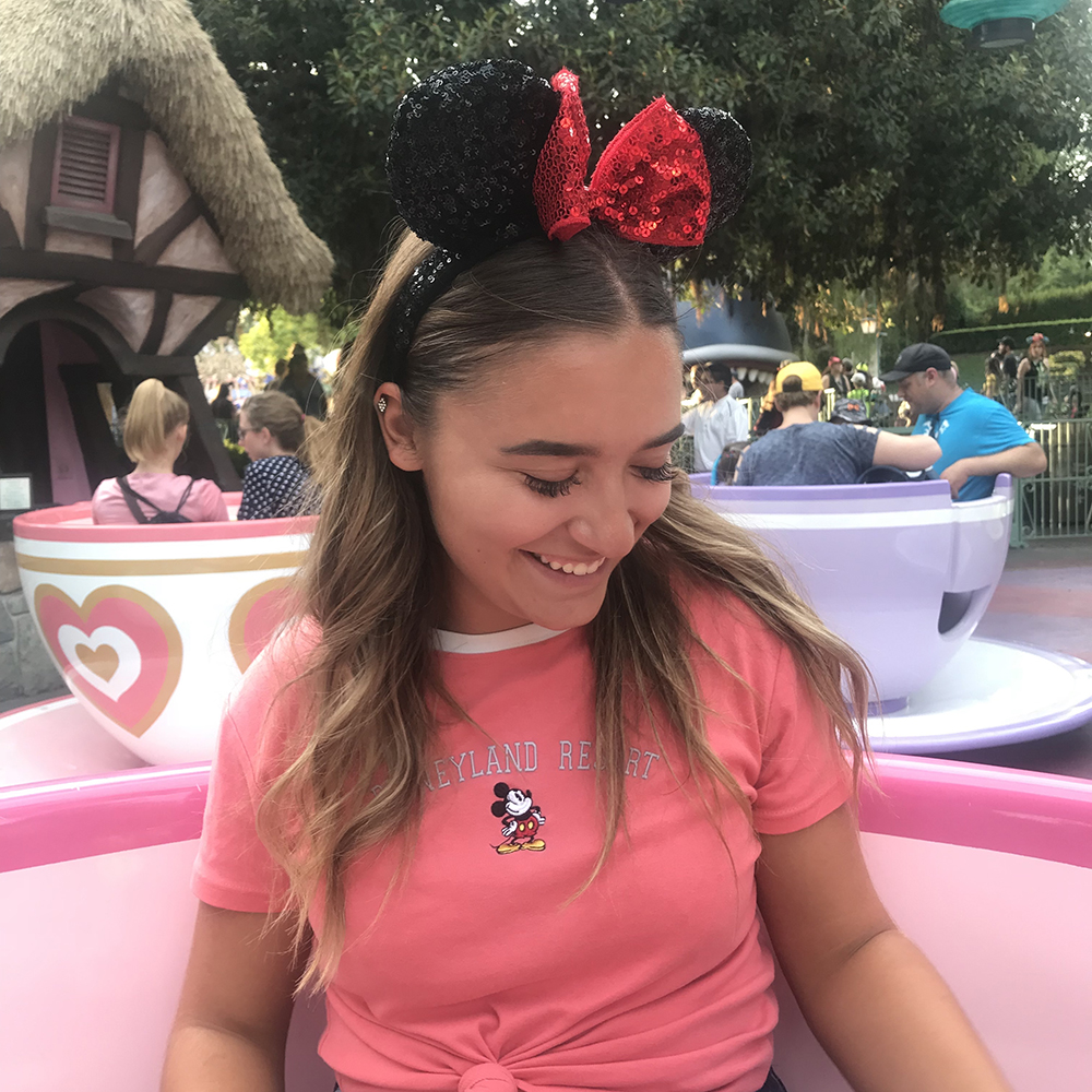 Kyra smiling while riding the Mad Tea Party. Kyra is wearing Minnie Mouse ears