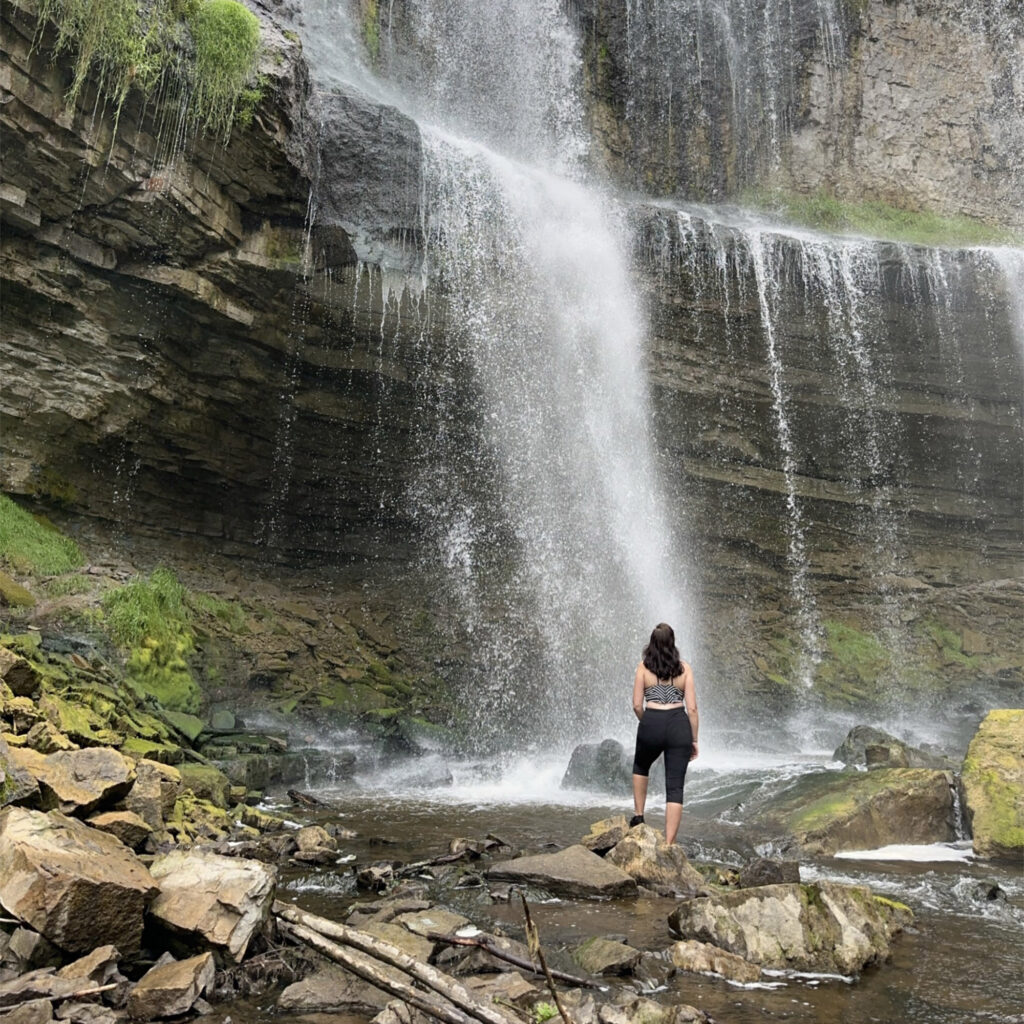 Jaime in front of a waterfall looking up at it