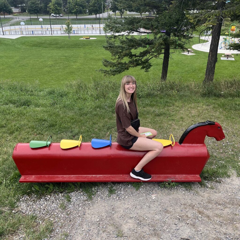 Liz sitting on a red steel horse playground feature
